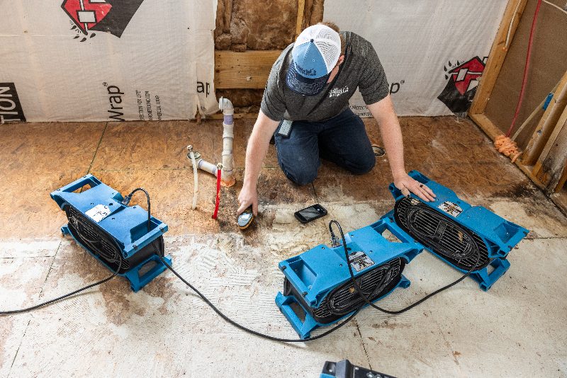 A moisture meter reading being taken on a water damaged subfloor