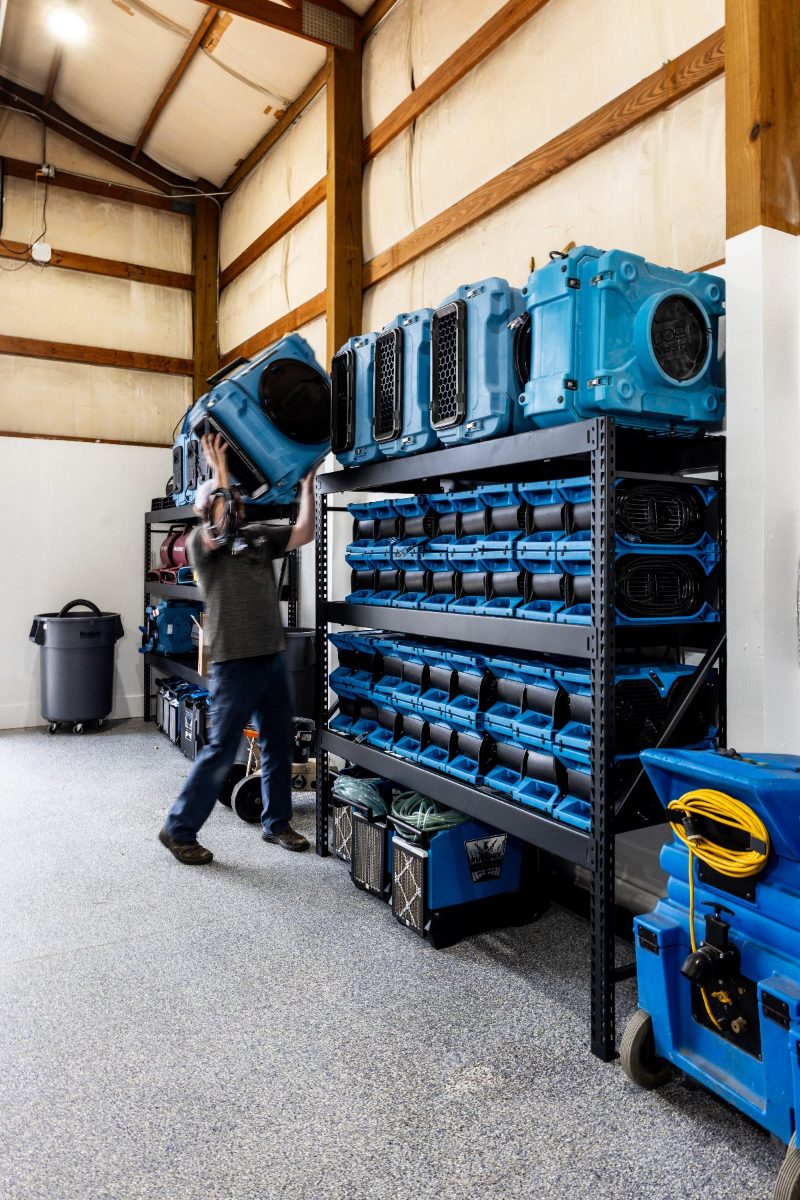 A technician pulling drying equipment from the stocked shelves at the shop
